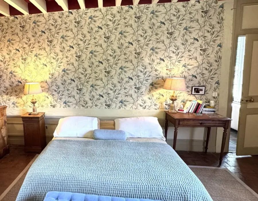 Chambre cosy avec lit, banquette bleue et papier peint floral